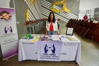 Woman standing behind a health awareness booth with informational materials.